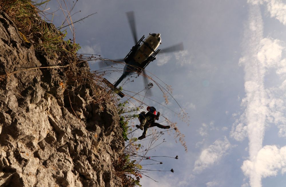 Bergretter und ´verletzter Kletterer´ werden nach erfolgreicher Kapp-Rettung vom Fels geflogen 