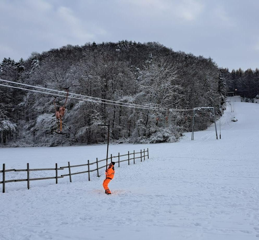 Ein MItarbeiter des Skilifts beim Anbringen eines Bügels an das Zugseil (Bild: Horst Fischer)