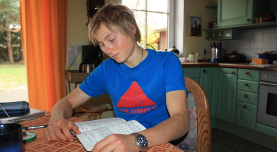 Alexander Megos brütet über seinem Routenbuch. Er ist im übrigen ein Anhänger der handgeschriebenen Version
