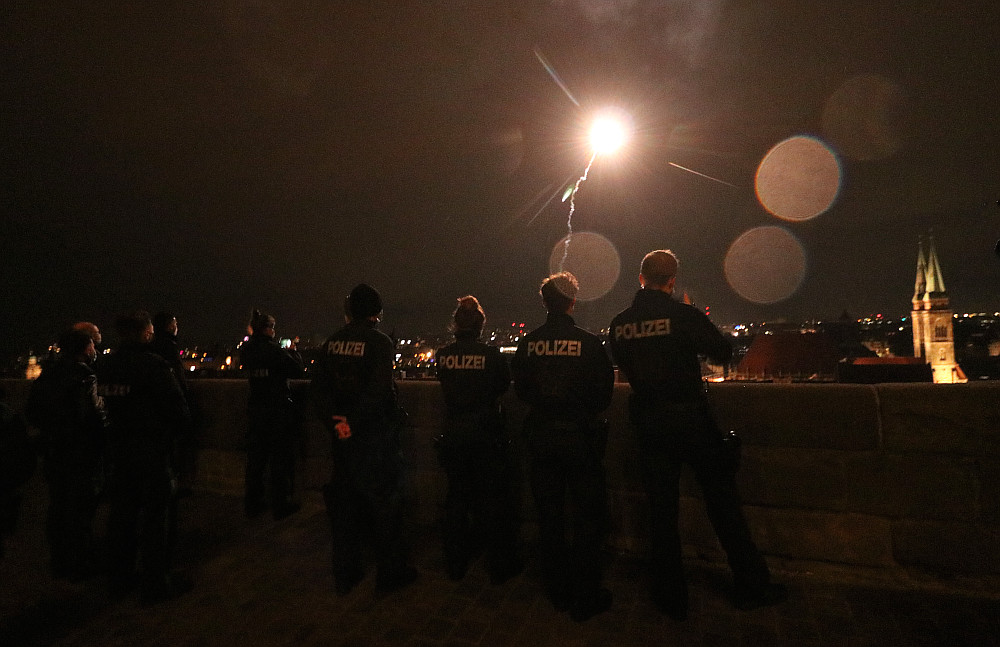 Eine kleine Gruppe bayerischer Bereitschaftspolizisten beobachtet zum Jahreswechsel eine von geschätzt zehn Raketen über der Nürnberger Altstadt